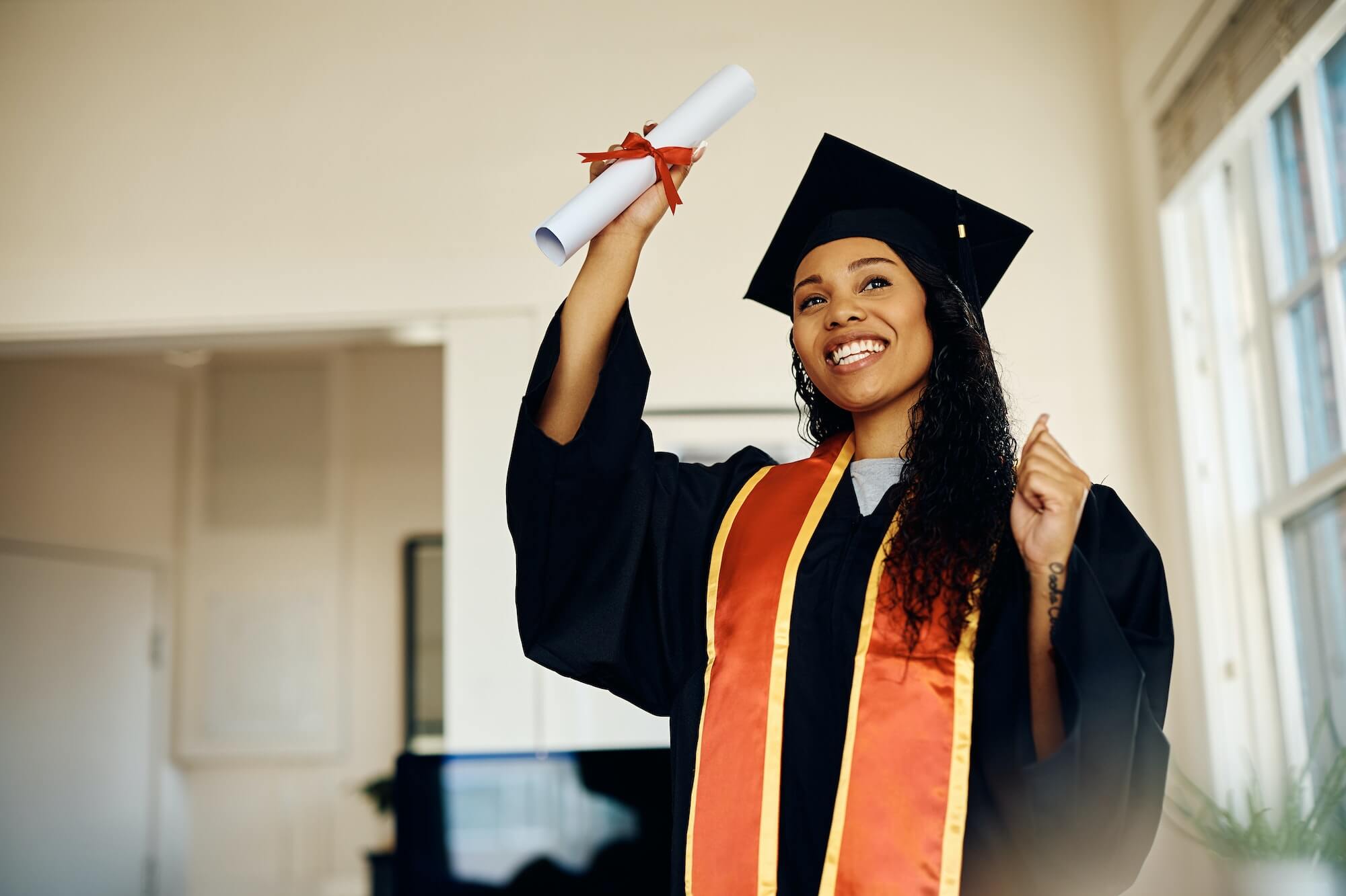 Happy black student celebrating her graduation at home.