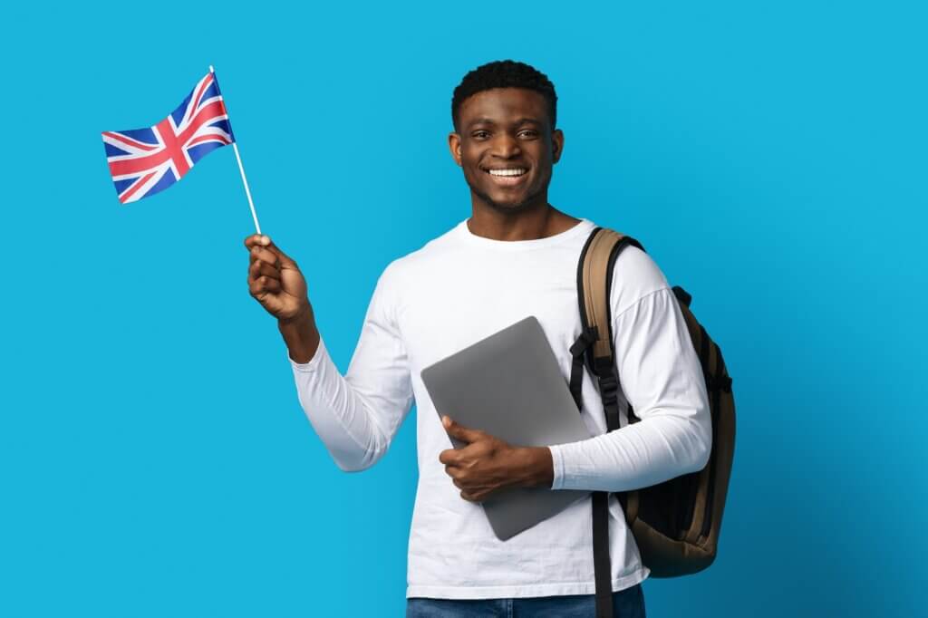 Smiling black man holding laptop and flag of UK